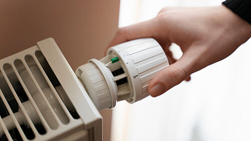 Person adjusting a radiator thermostat