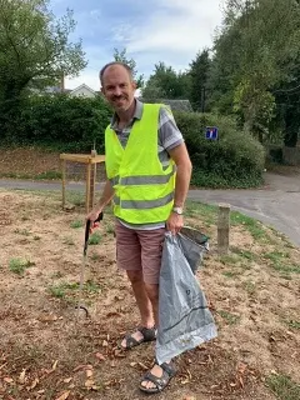 Photo of Richard Morris picking up litter in a hi-vis jacket