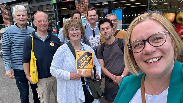 Zoe taking a selfie outside of Coop with a group of Lib Dem volunteers stood behind her smiling