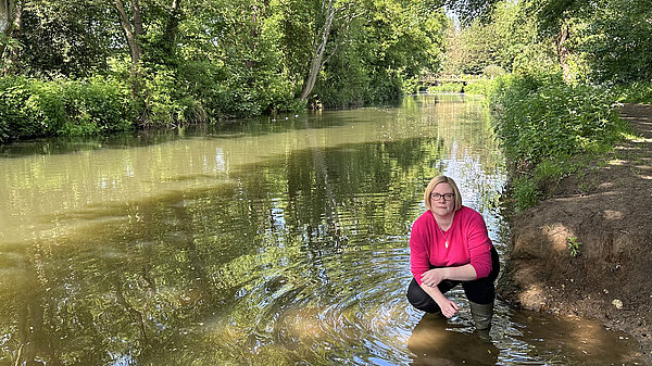 Zoe crouches in the river